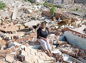 Dona de casa Betania Bonfim sentada nos escombros de sua casa derrubada para obras das margens da represa Billings