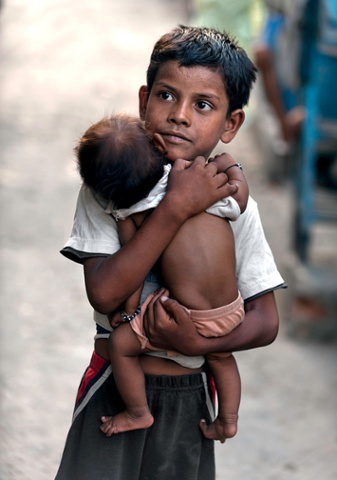 Vishal Singh, aged 6, cares for a baby girl while her mother is away, in the Kusum Pahari slum in south Delhi, India. Vishal is lucky in one way, when he is not working he is able to attend a school for slum children.